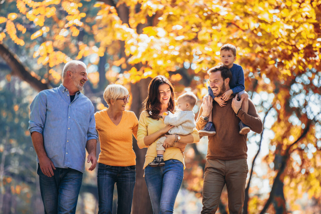 Familia de varias generaciones divirtiéndose en un parque otoñal.
